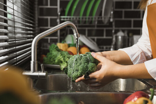Asian hands woman washing vegetables broccoli and preparation healthy food in kitchen.