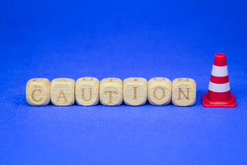 maintenance cones and words of caution on wooden cubes with blurred backgrounds