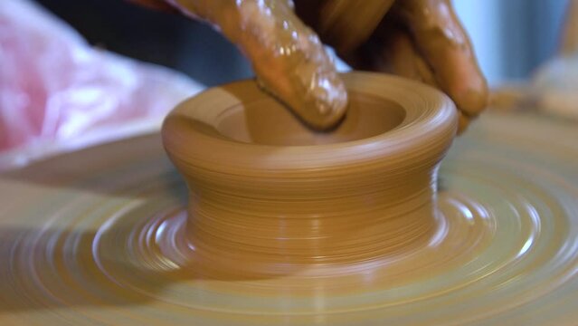 Close-up of hands making pottery on a wheel. Pottery workshop with a Potters wheel.