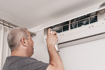 man master installer working and cleaning air filter on a indoor unit air conditioner at client's home © Елена Гурова