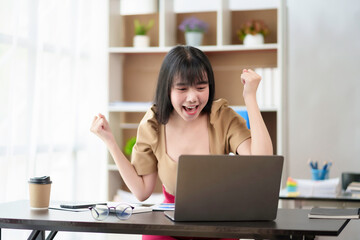 Beautiful Asian businesswoman who is excited about her laptop computer and accomplished and accomplished goals, happy and satisfied with her.