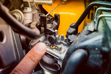 Fototapeta premium The finger points to the adjusting screw on the carburetor of the gas generator