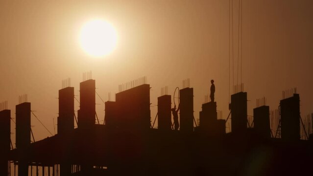 Silhouettes of builders working on construction site at sunset.