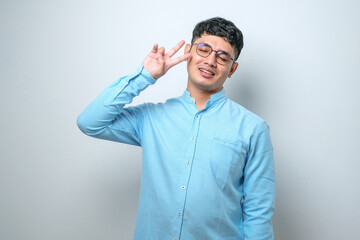 Young handsome asian guy doing peace symbol with fingers over face, smiling cheerful showing victory