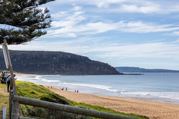 Seaside road winding along calm beach and rocky headland on sunny day