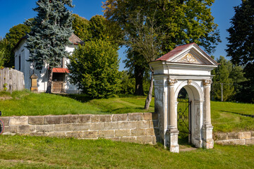 Fototapeta na wymiar Classicist gate at the entrance to a country cemetery with a baroque chapel