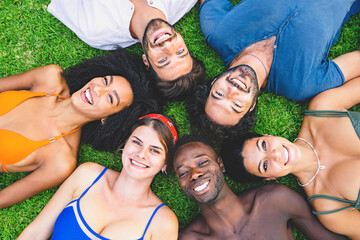 Top view of diverse team of friends relaxing in park lying on grass in circle - multiethnic group...