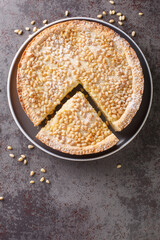 Italian Grandma's cake Torta della nonna Pine nut custard tart from Tuscany closeup in the plate on the table. Vertical top view from above