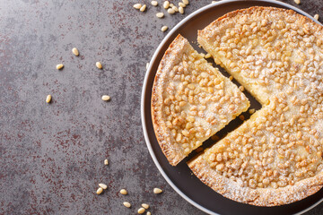 Torta della Nonna a soft flat italian cake flavoured with pine nuts closeup in the plate on the table. Horizontal top view from above