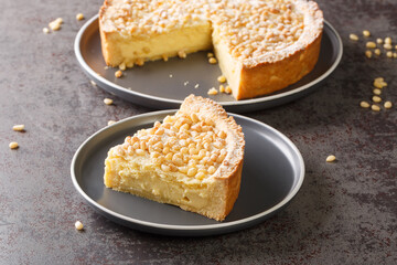 piece of Italian grandma's pie with custard and pine nuts close-up in a plate on the table. Horizontal