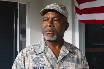 African american military senior man in camouflage clothing and cap looking away against house