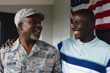 Happy african american military senior man looking at smiling mid adult son against house