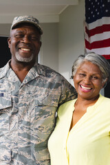 Portrait of african american military senior man in camouflage clothing with wife against house
