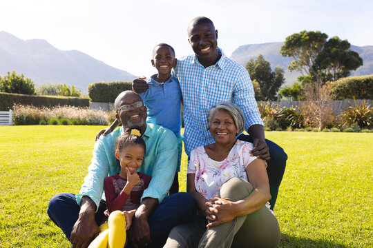 Portrait of happy multiracial multigeneration family enjoying leisure time on grassy field in yard