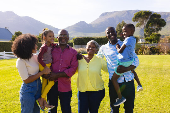 Cheerful Multigeneration Multiracial Family With Arms Around Enjoying Leisure Time In Yard