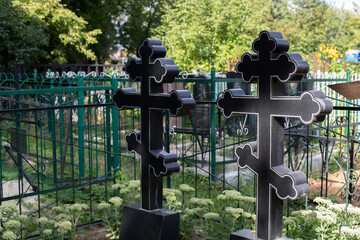 Two black stone crosses in a Christian cemetery, death grave of the cemetery
