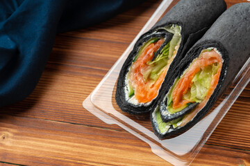 Black tortilla wrap with salted salmon and vegetables
