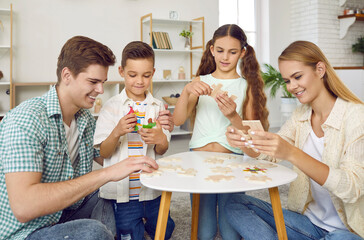 Happy family enjoying quiet games at home. Mother, father and little children sitting around a...