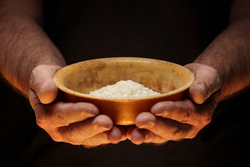 Hands holding a heap of dry rice grain on black background