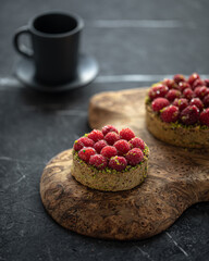 Raspberry tartlets with pistachios and coffee on serving board