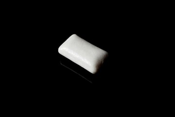 white cube of chewing gum on a black background close-up