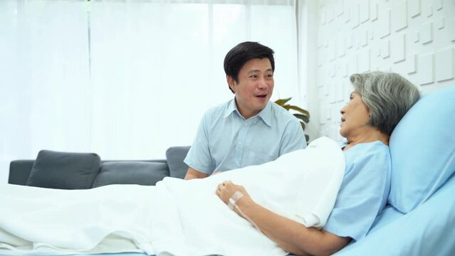 Son of an elderly woman patient shake hands and encourage his mother be admitted to the hospital. Female patient smiled brightly as she was encouraged by her son.