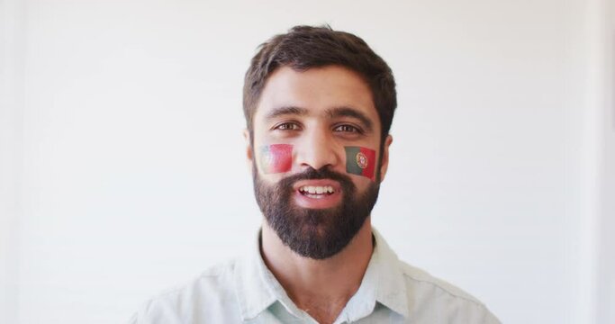 Image of happy middle eastern man with flag of portugal cheering