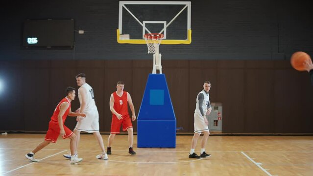 International basketball traning game, the confrontation between two teams, sporty lifestyle, mens active game at night time indoor.
