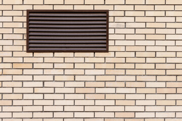 New large brown ventilation grate in modern yellow brick wall.