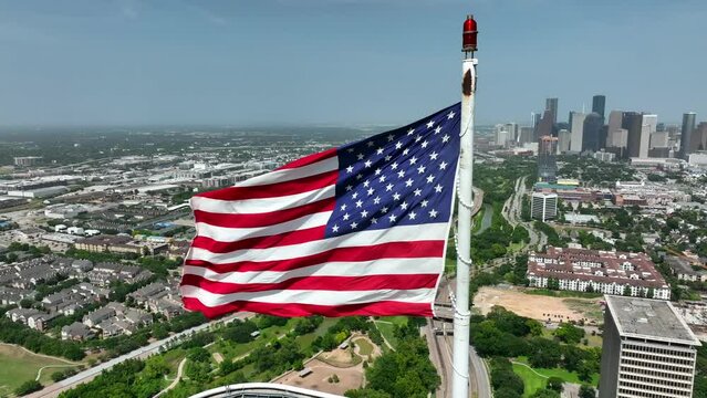 Houston Texas skyline. American flag proudly waves above cityscape. Aerial orbit. City in USA.