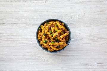 Obraz na płótnie Canvas Homemade One-Pot Cheeseburger Pasta in a Bowl on a white wooden background, top view. Flat lay, overhead, from above.