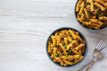 Homemade One-Pot Cheeseburger Pasta in Bowls on a white wooden surface, top view. Flat lay, overhead, from above. Space for text.