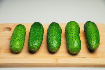 juicy green cucumbers lie nearby on a wooden cutting board, on the dining table. close-up