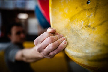 Male hand smeared with magnesium powder grabbing a hold of a climbing wall