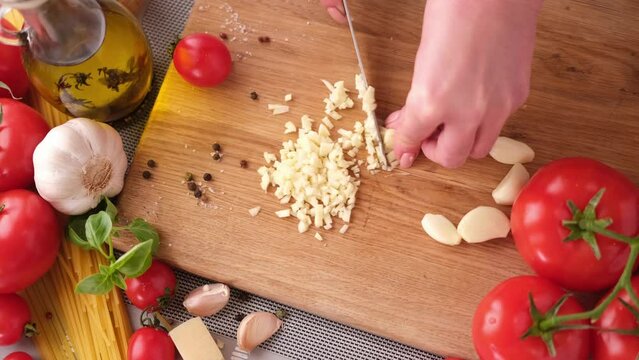 making pasta carbonara - cut garlic with knife on a wooden cutting board
