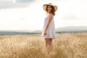 Woman in hat on the field with flowers on the field background