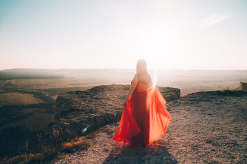 A girl in a red dress on the background of the mountains lifestyle. Illustrating articles about...