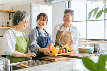 野菜を持つ高齢者夫婦と若い日本人（家事代行・介護）
