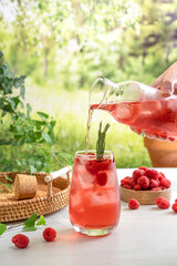 Summer refreshing non-alcoholic cocktails. Raspberry lemonade garnished with fresh rosemary. Summer raspberry beverage with sparkling water. Copy space.
