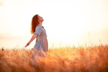 Woman in the field with flowers on sunset background