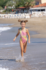 A happy little girl runs along Cleopatra Beach in Alanya, Turkey.