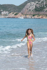 A happy little girl runs along Cleopatra Beach in Alanya, Turkey.