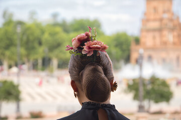 Detail of hairstyle of young teenage woman with pink carnations in her hair. Flamenco concept, dance, art, typical Spanish dance, hairstyle, flowers.