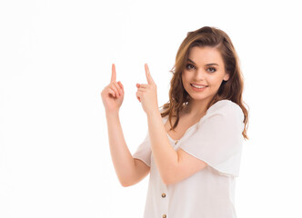 A young girl points her fingers at an empty space on a white background.