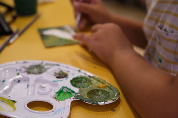 a little girl paints with paints