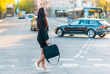 Young pretty business woman commuting and walking in city street with laptop bag.Side view,copy space.full-length.