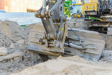 The digger is working on road repairs.Road works. Road repair in small town.Close up.