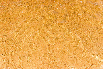 Abstract Transparent and clean yellow water background with sunlight reflection, top view,summer natural day shot.Copy space.
