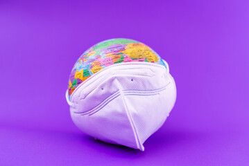 Fototapeta premium World Planet Earth with face mask protect flat lay on the purple ,veri peri background.World medical concept.