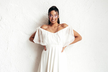 Young beautiful smiling female in trendy summer dress clothes. Sexy carefree woman posing near white wall in studio. Positive model having fun and going crazy. Cheerful and happy. In sunglasses